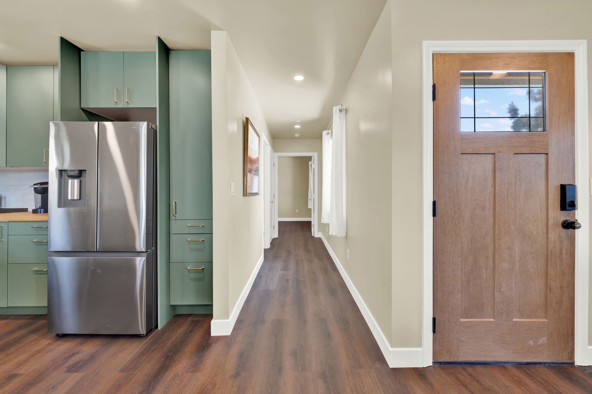 The hall off the kitchen. The cabinet run wraps the refrigerator and keeps the walkway clear.
