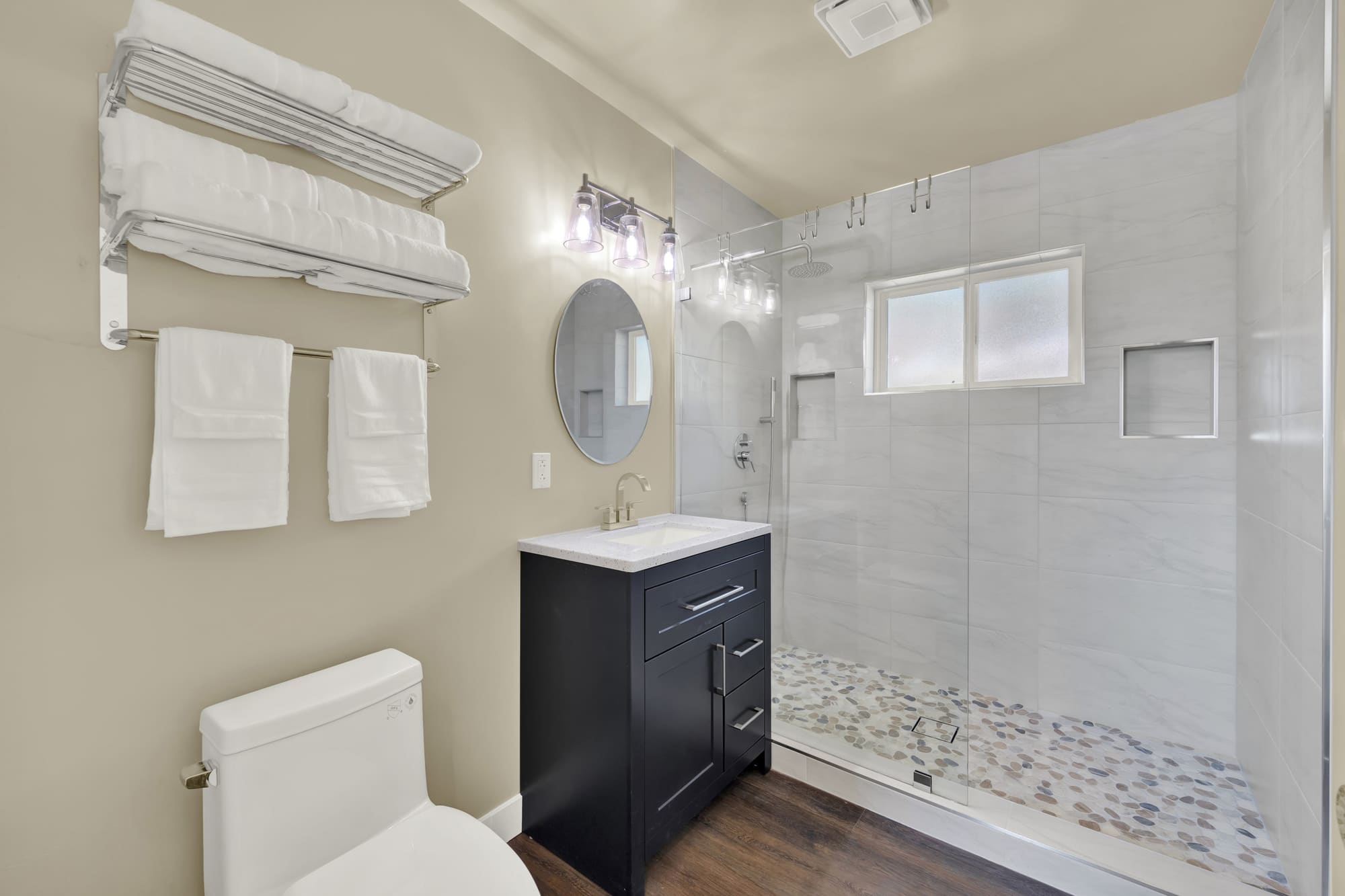 The full bath. Charcoal vanity, quartz top, and a walk-in shower behind frameless glass.