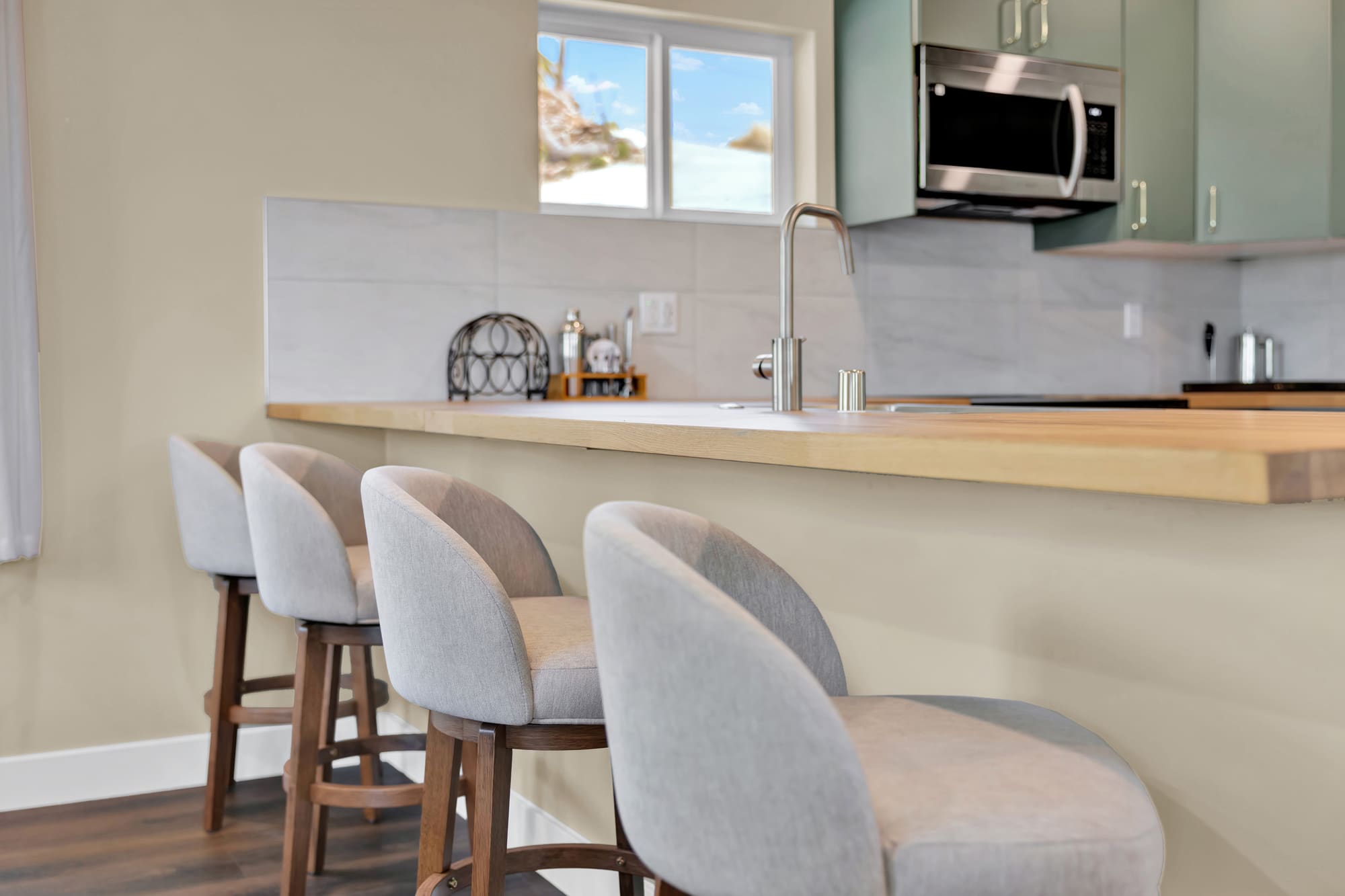 The butcher block runs past the cabinets to make a bar top with room for four. One continuous slab, no seam at the corner.