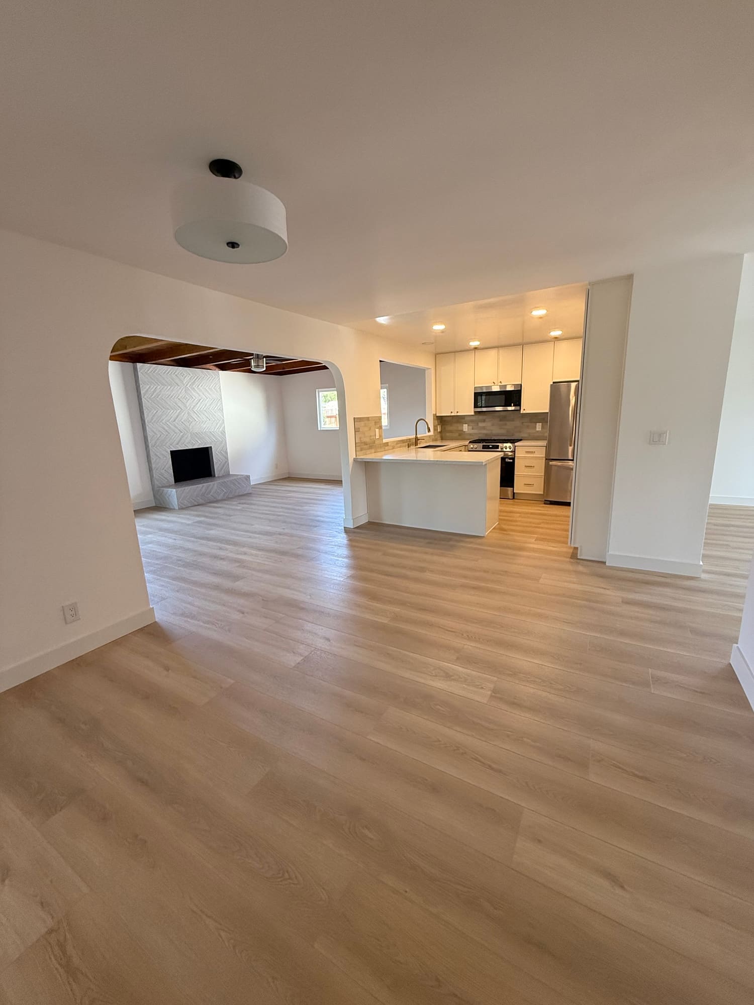 Empty, before staging, which is the clearest look at the plan. Dining in front, kitchen right, and the arched opening through to the living room.